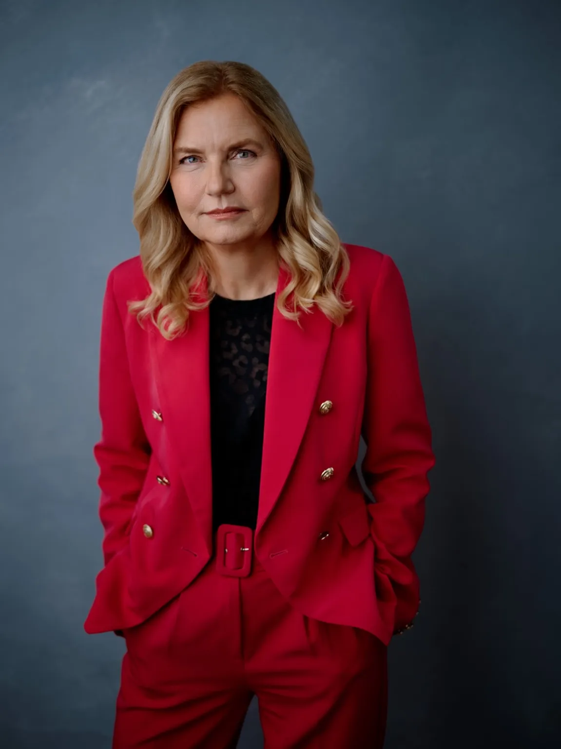 Barbara Wichmann wearing a bright pink suit against a slate-blue studio backdrop