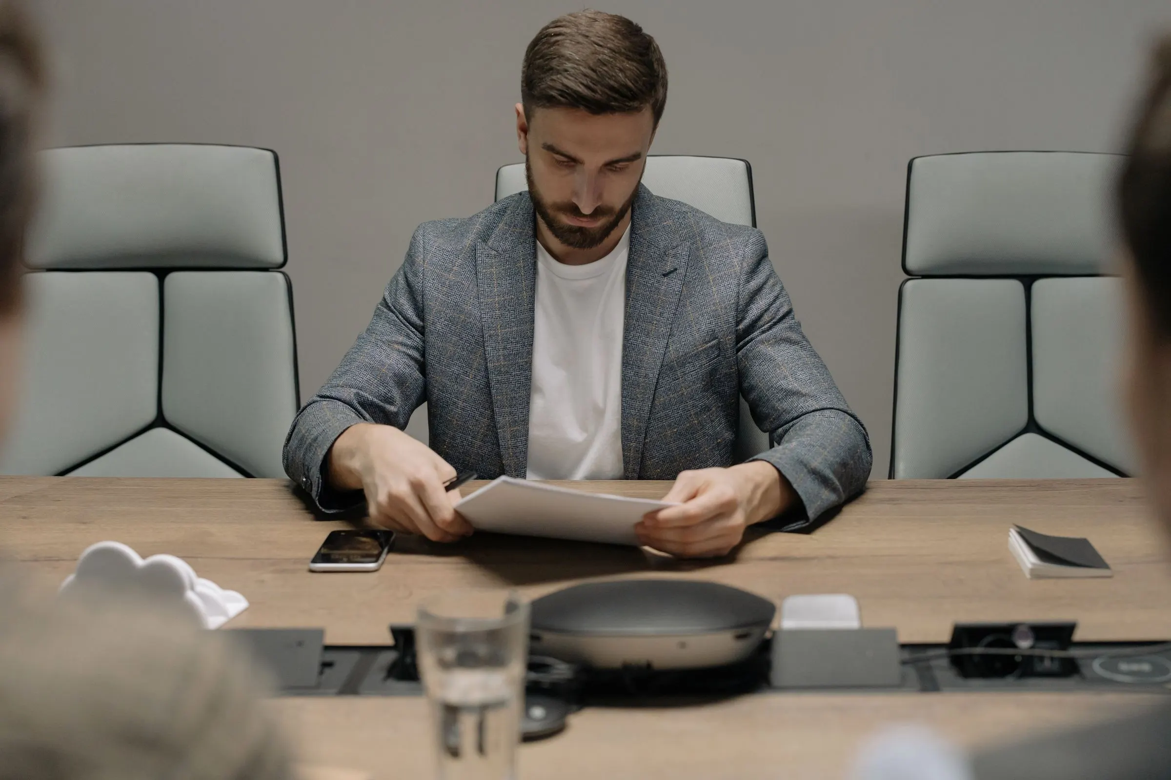 A focused businessman reads documents at a conference table, preparing for a meeting.